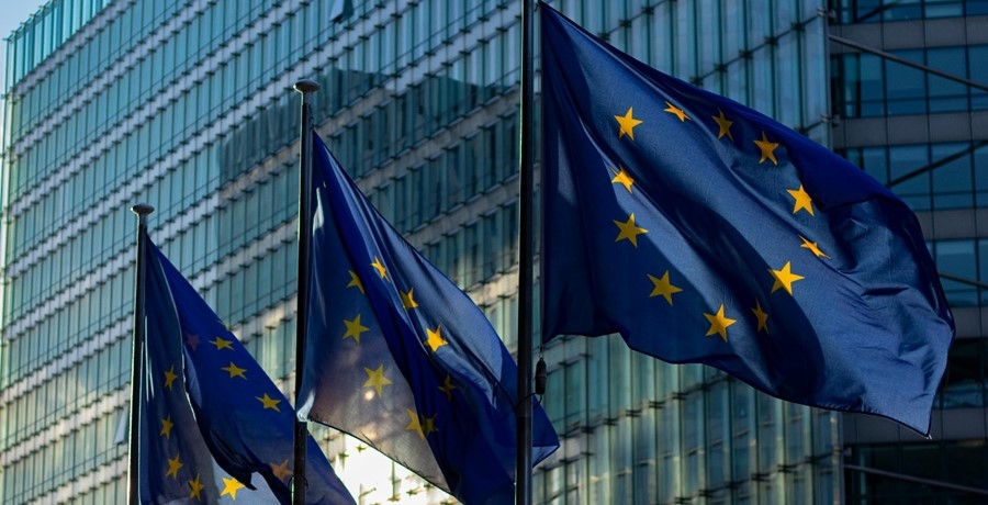 3 EU-Fahnen wehen im Wind vor einem Hochhaus